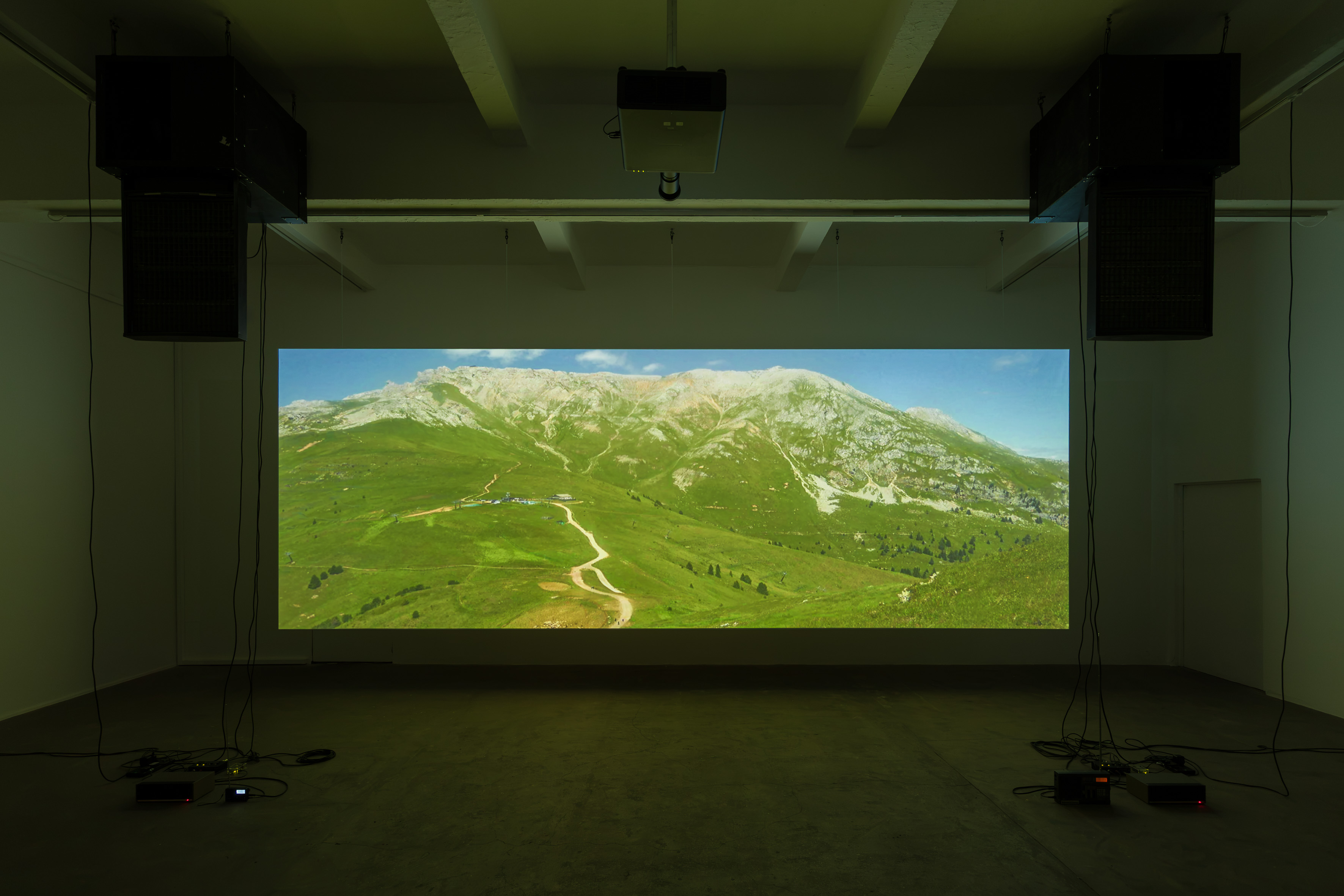 Wide view of the STILL LIFE gallery hardware system with projection, suspended speakers, cabling and floor electronics.